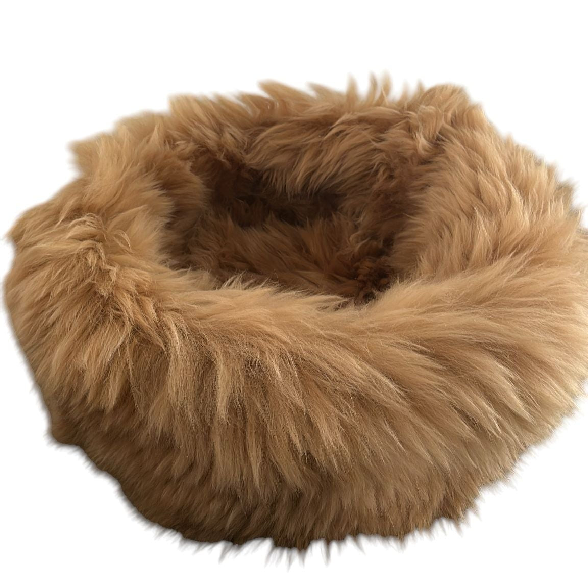 ein runder Korb aus Schaffell in braun beige liegend auf dem Boden