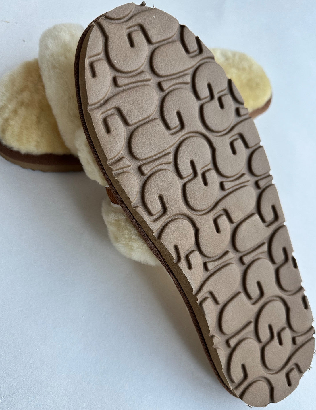Nahaufnahme der Sohle des Schlappens von LIRA Deko in Beige/Creme mit strukturiertem Muster mit Rillenformen. Der aus kuschlig hellbeigem Material und echtem Lammfell gefertigte Slipper bietet ein weiches und gemütliches Tragegefühl. Der schlichte weiße Hintergrund betont die Details der Sohle des strapazierfähigen Slipper.